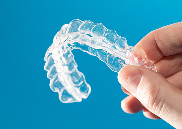 closeup of a person holding their clear aligners