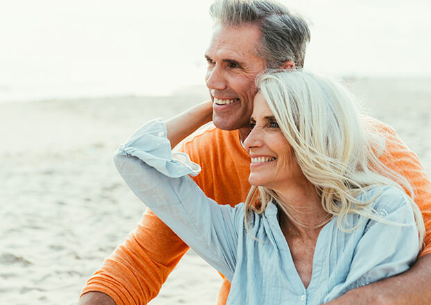 smiling senior couple sitting on the beach together