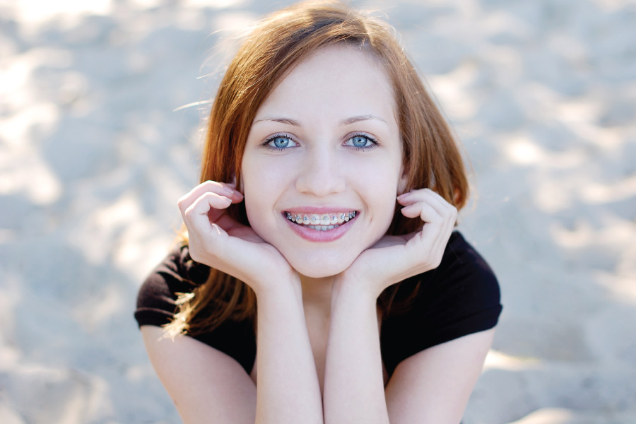 Redheaded girl smiles with her braces outside in Houston, TX